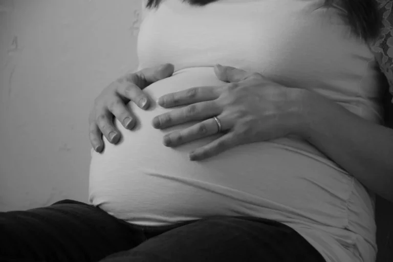 Manos sobre la barriga de una embarazada, en blanco y negro