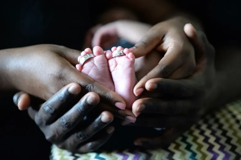 Pies de un recién nacido entre las manos de su padre