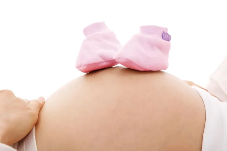Patucos rosas sobre la barriga de una embarazada